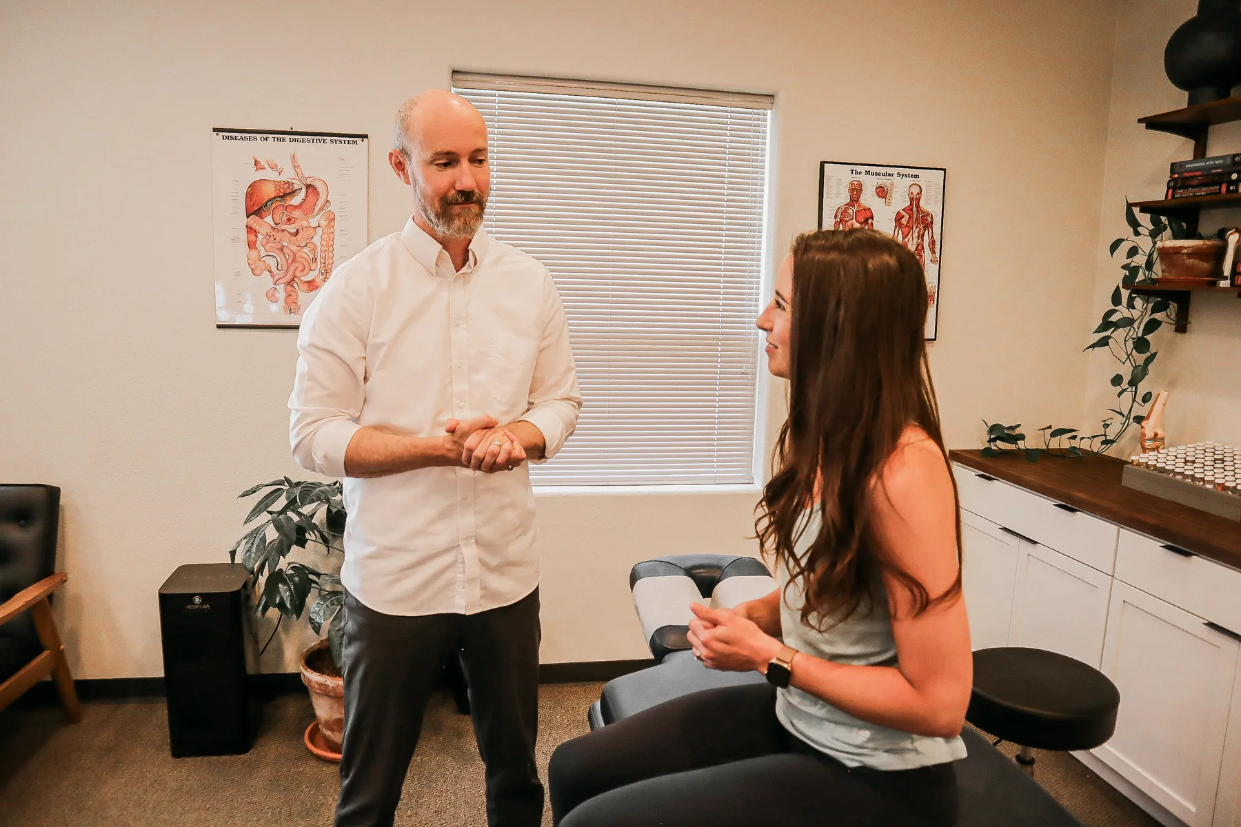 Dr. Andrew Rostenberg consulting with a patient in front of a digestive system anatomy chart at Red Mountain Natural Medicine in Boise, Idaho — gut and liver function are central to natural detox