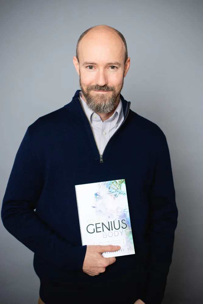 Dr. Andrew Rostenberg holding his book Your Genius Body